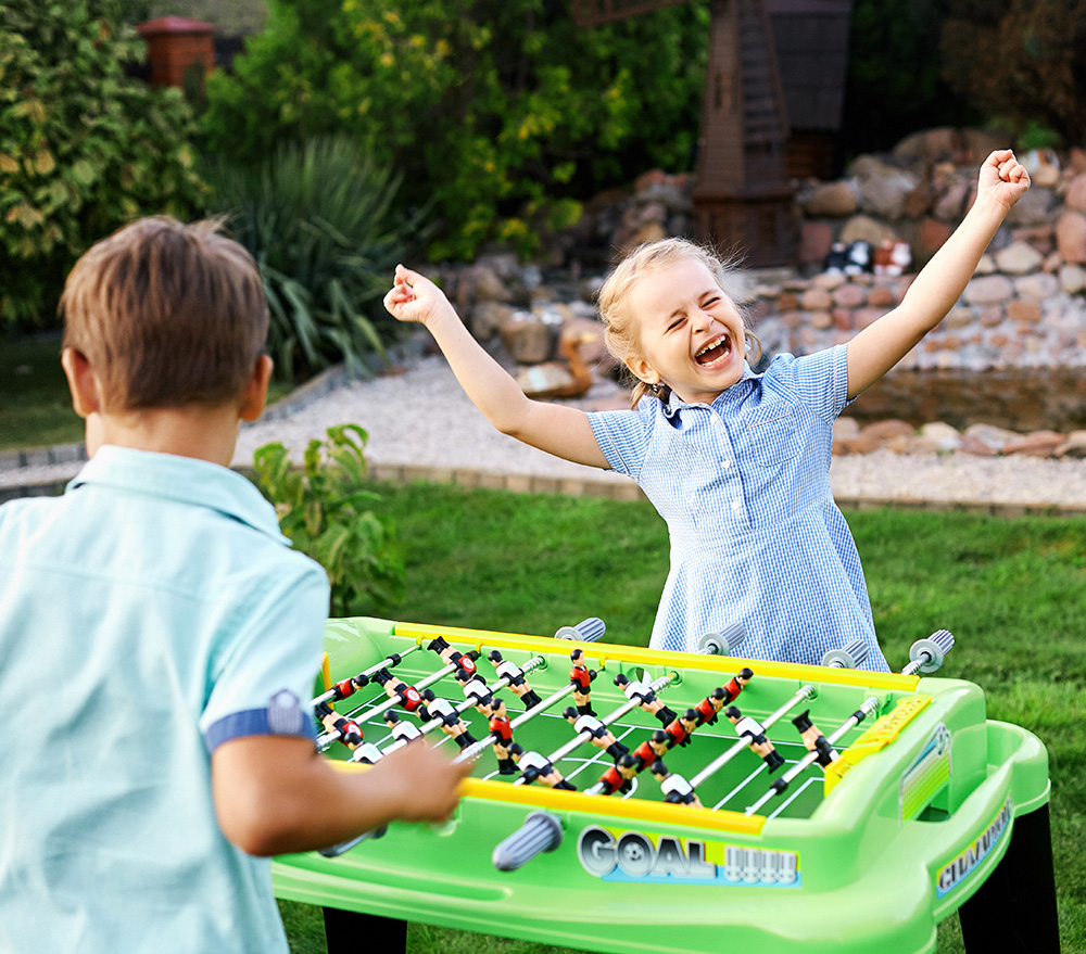 two children playing foosball outside